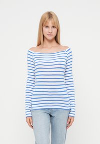 Μπλε και λευκή ριγέ μπλούζα με μακριά μανίκια και σχεδιασμό που αφήνει τους ώμους ακάλυπτους. Απαλή ύφανση, εφαρμοστή γραμμή και ίσια ραφή στο κάτω μέρος. Συνδυάζεται με ανοιχτόχρωμο τζιν παντελόνι.