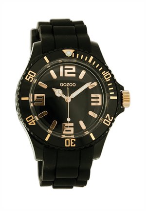 Black silicone watch with a round face, gold accents, large numerals, and a transparent bezel. Features a textured band for grip.