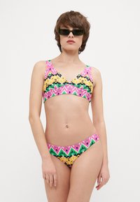 Ensemble de bikini coloré comprenant un haut à motifs avec de larges bretelles et un design en V, complété par un bas taille basse assorti.