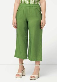 Groene, lichte, cropped broeken met een elastische tailleband en een geplooide textuur, gecombineerd met beige platformsandalen.