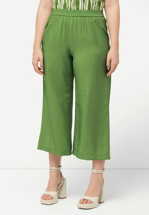 Grüne, leichte, cropped Hosen mit elastischem Bund und knitteriger Textur, kombiniert mit beigen Plateausandalen.