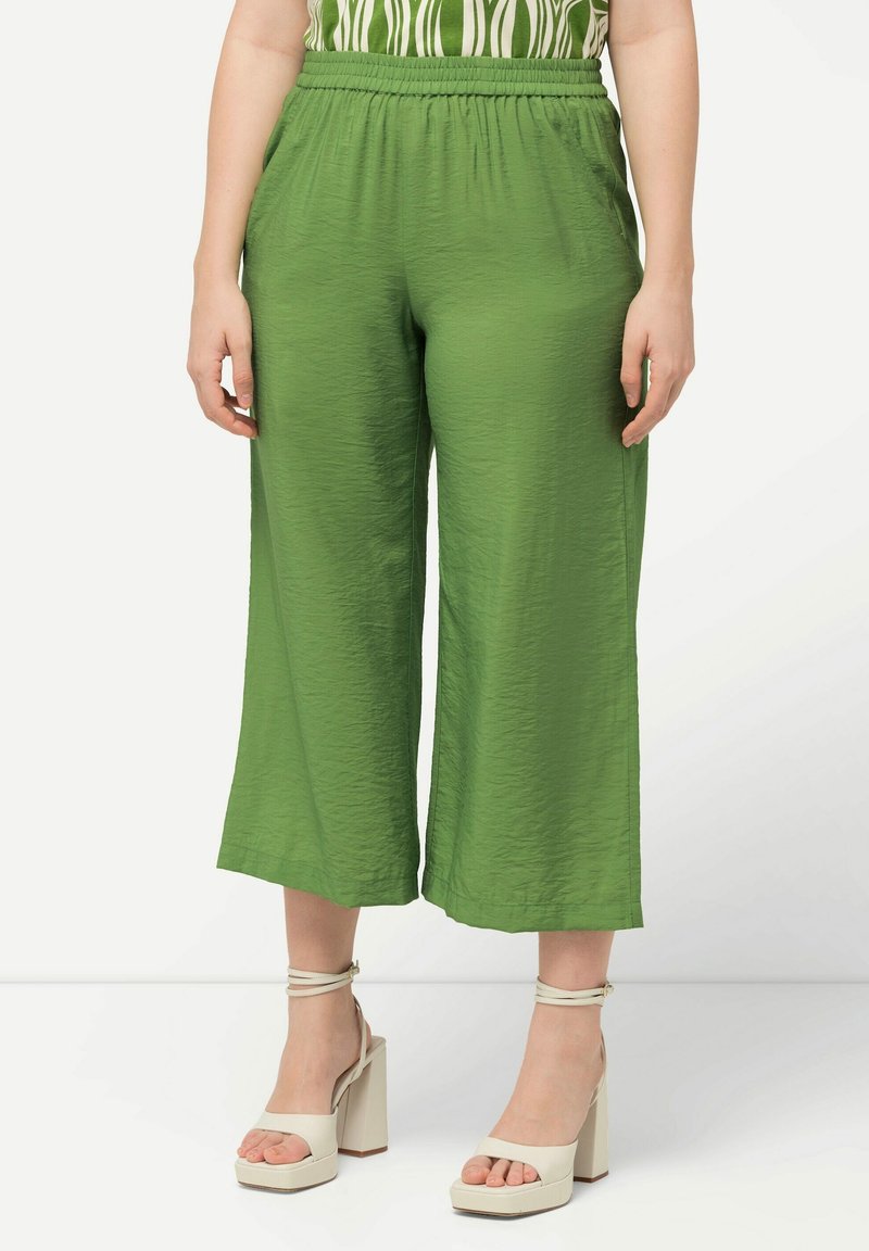 Groene, lichte, cropped broeken met een elastische tailleband en een geplooide textuur, gecombineerd met beige platformsandalen.