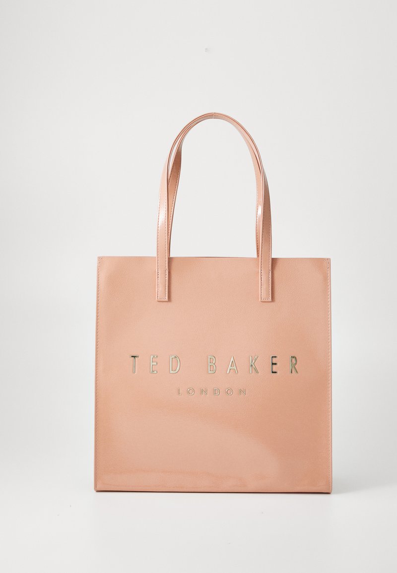 Ružová taška z faux kože s dvoma uchami, na prednej strane s embosovaným zlatým nápisom "TED BAKER LONDON" a hladkým, lesklým povrchom.
