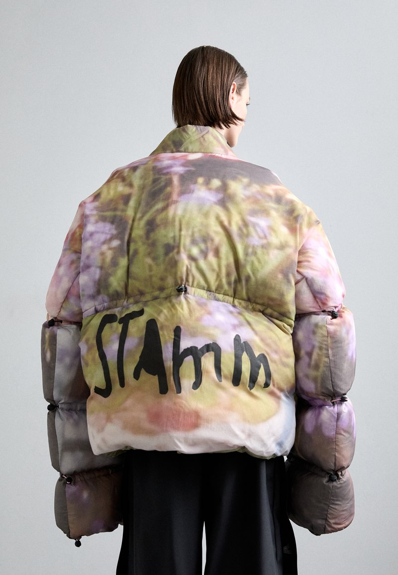 Nafouknutá bunda s barevným květinovým potiskem, s vysokým límcem a volným střihem. Černý nápis "STAm" na zadní straně. Hladká textura.