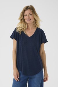 Jūras spēku zilas krāsas V-veida kakla blūze ar īsām piedurknēm, kas izgatavota no teksturēta acs auduma un ar brīvu piegriezumu, kombinēta ar zilu džinsu biksēm.