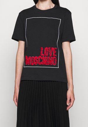 Zwart T-shirt met korte mouwen met een wit omlijnd vierkant en rode gestructureerde tekst "LOVE MOSCHINO" erin, gedragen met een zwarte geplooide rok.