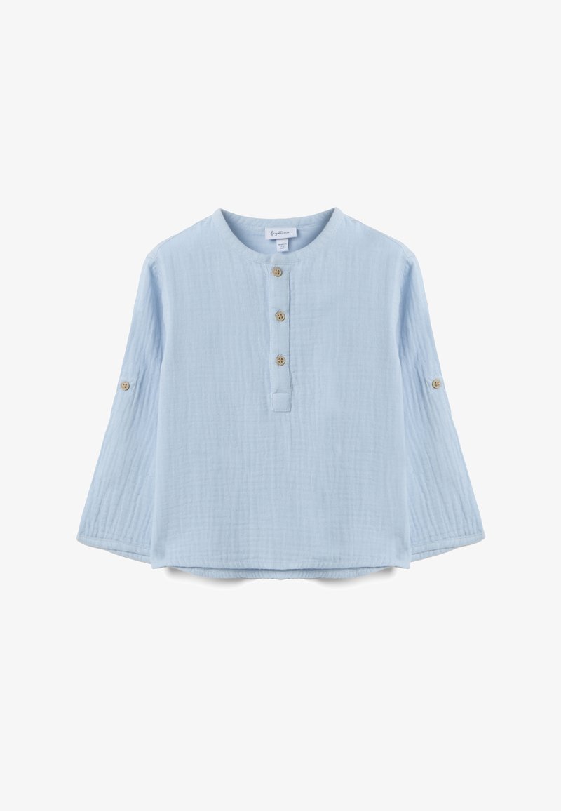 Chemise à manches longues bleu clair pour tout-petit, avec encolure ronde, trois boutons sur le devant et des pattes à boutons sur les manches pour les retrousser.