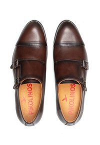 Bruine leren schoenen met een gladde textuur, voorzien van een dubbele gesp en een ronde neus. De binnenkant heeft een rood logo op een beige inlegzool.