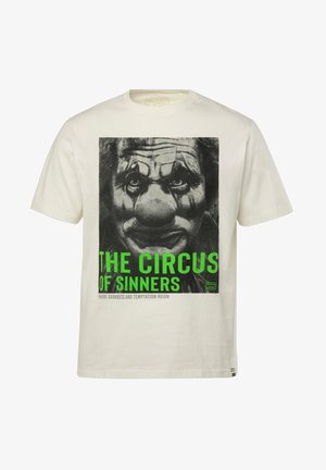 T-shirt en coton crème avec un graphique de visage de clown en noir et blanc et un texte vert indiquant "LE CIRQUE DES PÉCHEURS" en dessous.