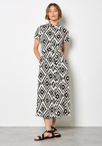 Schwarzes und weißes gemustertes Hemdkleid mit kurzen Ärmeln, Kragen, tailliertem Bund und Taschen, das ein geometrisches Diamantdesign aufweist.
