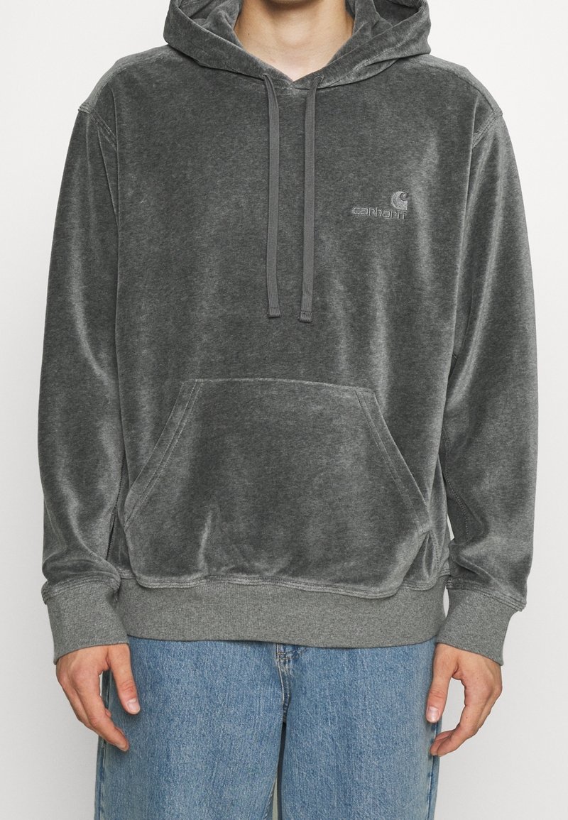Sudadera gris hecha de suave tela de terciopelo; cuenta con un bolsillo frontal, capucha con cordón y un pequeño logo en el pecho. Corte clásico con puños de canalé.