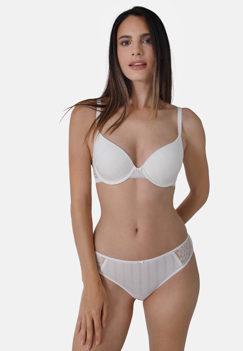 Weißer BH und passender Unterwäsche, mit glatter Stoffoberfläche, gerippten Texturen, Spitzenakzenten und semitransparenten Einsätzen an den Seiten.