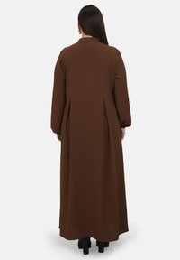 Dlouhé hnědé šaty s přiléhavým korzetem, sklady v pase a dlouhými rukávy. Texturovaná tkanina s volným siluetou.