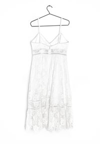 Vestido de encaje blanco con tirantes finos ajustables, que presenta patrones florales, un dobladillo en forma de escalloped y un corsé ajustado con un largo medio fluido.