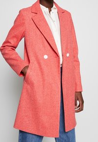 Cappotto in misto lana corallo con motivo a spina di pesce, design doppiopetto, rever a punta e tasche laterali.