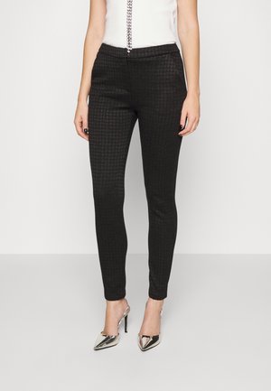 Zwarte katoenen broek met een slim fit, voorzien van een zachte textuur en een elastische tailleband. Gekoppeld met metallic hoge hakken.