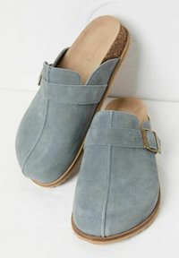 Gray suede clogs with an adjustable strap, cork footbed, and rubber sole. Features a rounded toe and subtle stitching details.