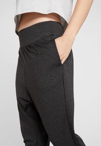 Svarta träningbyxor i mjukt, stretchigt material. Har en bred elastisk midjeband och sidofickor. Inkluderar en liten Puma-logotyp.