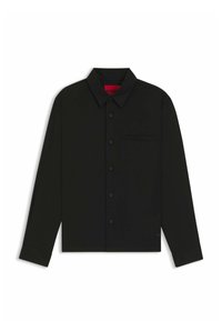 Chemise noire à manches longues avec col boutonné, poche poitrine unique et boutons sur le devant. Présente une texture lisse et une étiquette interne rouge.