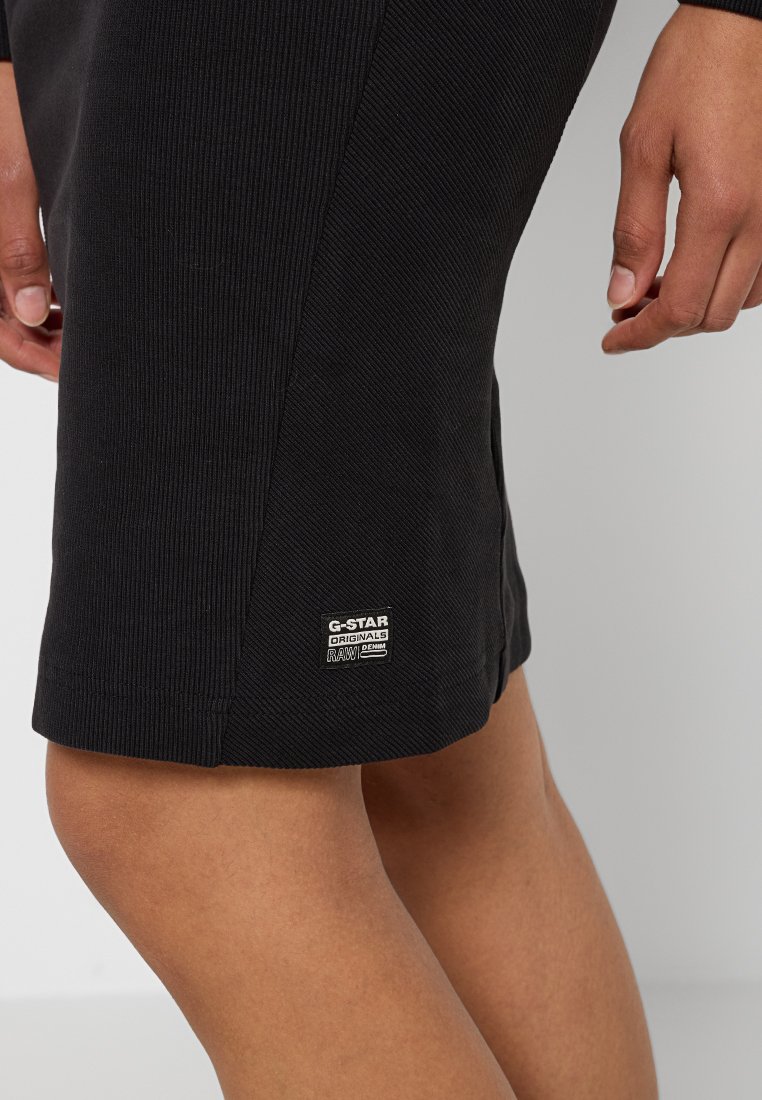 Jupe en tissu noir côtelé avec fente latérale, arborant une étiquette G-Star Originals près de l'ourlet. Conception texturée avec une silhouette ajustée.