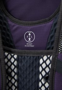 Tissu violet avec un motif en maille et des accents noirs. Présente une étiquette "Ajustement de la hauteur" avec une icône, soulignant des éléments de conception ajustables.