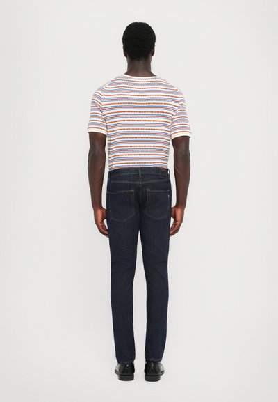 Camiseta de manga corta a rayas con líneas naranjas, azules y blancas, combinada con jeans de mezclilla de color azul oscuro. Corte estándar con bolsillos, sin logotipos visibles.