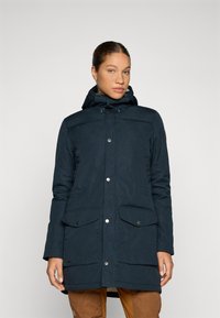Navy parka met capuchon, voorzien van drukknoopsluitingen, twee voorzakken en een gestructureerde afwerking. Ontworpen voor warmte en functionaliteit.