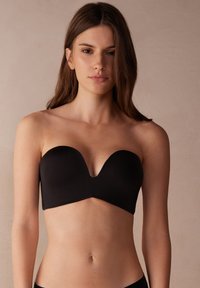Czarny stanik bez ramiączek wykonany z gładkiego materiału, z dekoltem w serek i bezszwowymi miseczkami, zaprojektowany z myślą o pewnym dopasowaniu i komforcie.