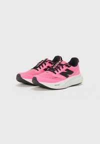 Zapatillas deportivas rosas con una parte superior de malla y acentos negros. Cuentan con una suela blanca, cordones negros y un logo 'N' prominente en el costado.