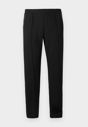 Zwarte sweatpants met een elastische tailleband, taps toelopende pijpen en zijzakken. Het materiaal lijkt zacht met zichtbare stiksels.