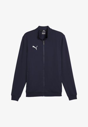 Marineblaue Zip-Jacke aus glattem Material, mit hohem Kragen, seitlichen Taschen, gerippten Bündchen und einem weißen Puma-Logo auf der Brust.