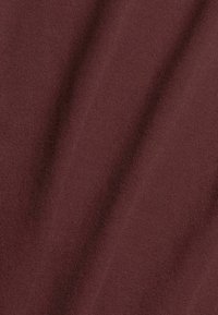 Tessuto di maglia color bordeaux con una trama liscia e leggermente rigata, che mostra un colore morbido e uniforme su tutto il materiale.