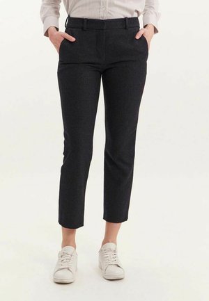 Pantalons slim en noir et gris à carreaux, avec un devant plat, deux poches latérales et des poignets retroussés, associés à des baskets blanches.