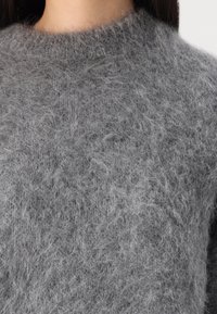 Grauer Wollpullover mit einer weichen, flauschigen Textur und einem hohen, runden Ausschnitt. Bequem geschnitten und leicht im Design.