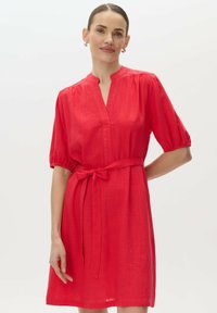 Czerwona sukienka do kolan wykonana z lekkiego materiału. Posiada dekolt w kształcie litery V, krótkie bufiaste rękawy oraz wiązany pasek w talii dla podkreślenia sylwetki.