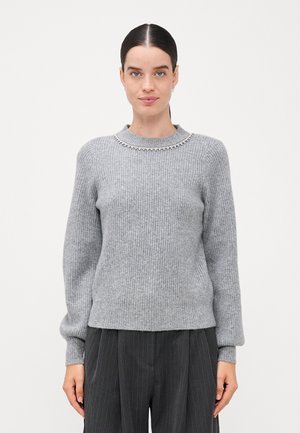 Pulover gri cu diafragme și guler rotund, embellisat cu mici pietre transparente în jurul gulerului. Purtați-l cu pantaloni închis de culoare cu dungi subțiri.