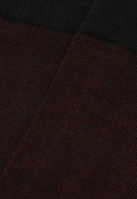 Strikket stof med et mørkerødt og sort farveblokdesign, der har en blød tekstur og subtile stræk, ideel til afslappet tøj.