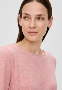 Helles Rosa, runder Hals-Pullover aus weichem Material, mit einer leicht strukturierten Oberfläche und dezenten Nähten entlang des Halsausschnitts.