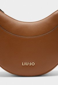 Bolso de mano de cuero marrón con un diseño curvado, que presenta una textura suave y un logo dorado "LIU JO" en la parte frontal. Detalle de cierre con cremallera visible.