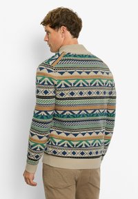 Strickpullover mit geometrischen Mustern in erdigen Tönen von Grün, Blau, Orange und Beige; gerippte Bündchen und Taillenbund; hohes Kragen-Detail.