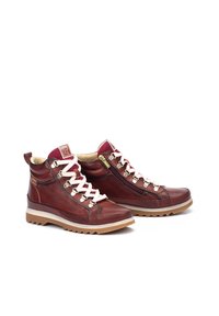 Bottines en cuir marron avec lacets blancs, fermeture éclair sur le côté et semelle en caoutchouc texturée. Présentent un col rembourré et des détails de couture contrastés.