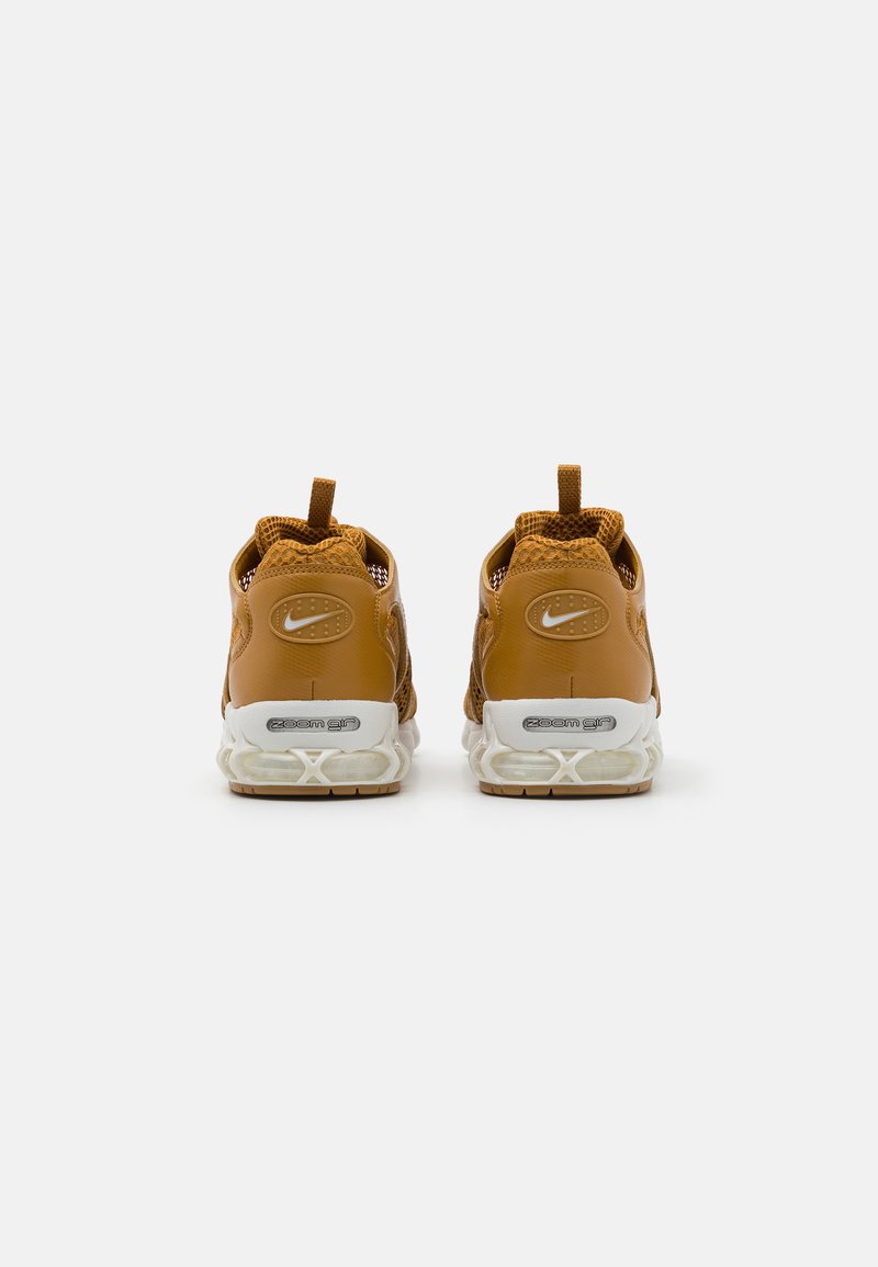 Baskets Nike Zoom Air en cuir brun et mesh avec semelles blanches. Présente une surface texturée, un col rembourré et une poignée à l'arrière.