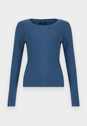 Zils ribots garām piedurknēm pieguļošs tops ar apaļu kakla izgriezumu uz vienkārša balta fona.