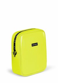 Harde reiskoffer in helder geel, met verticale ribbeltextuur, zwarte rits met logo en rechthoekig ontwerp.