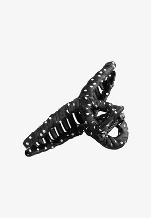 Schwarzer Haarklammer aus Kunststoff, umwickelt mit schwarzem Stoff mit weißen Polka-Dots, zeigt offene Federmechanik und gebogene Zinken.