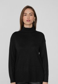 Schwarzer Rollkragenpullover mit langen Ärmeln, gerippten Bündchen und Saum, aus weichem Material gefertigt, mit lässiger Passform und minimalistischem Design.