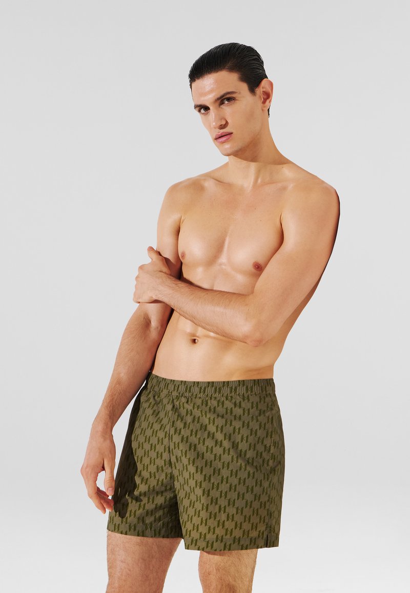 Costumi da bagno verdi con motivo a stampa, dotati di una fascia elastica in vita, caratterizzati da un discreto design geometrico e da una trama di tessuto leggera e morbida.