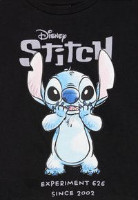 Crni majica s crtićem Stitchom, plave boje s velikim ušima, s natpisom "Disney Stitch" i "Eksperiment 626 Od 2002." ispod.