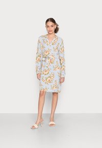 Vestido floral azul claro com mangas longas, decote em V, laço na cintura e comprimento até ao joelho. Apresenta padrões de flores laranja e verde.