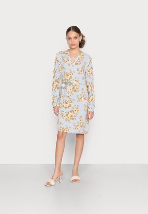 Vestido floral azul claro com mangas longas, decote em V, laço na cintura e comprimento até ao joelho. Apresenta padrões de flores laranja e verde.
